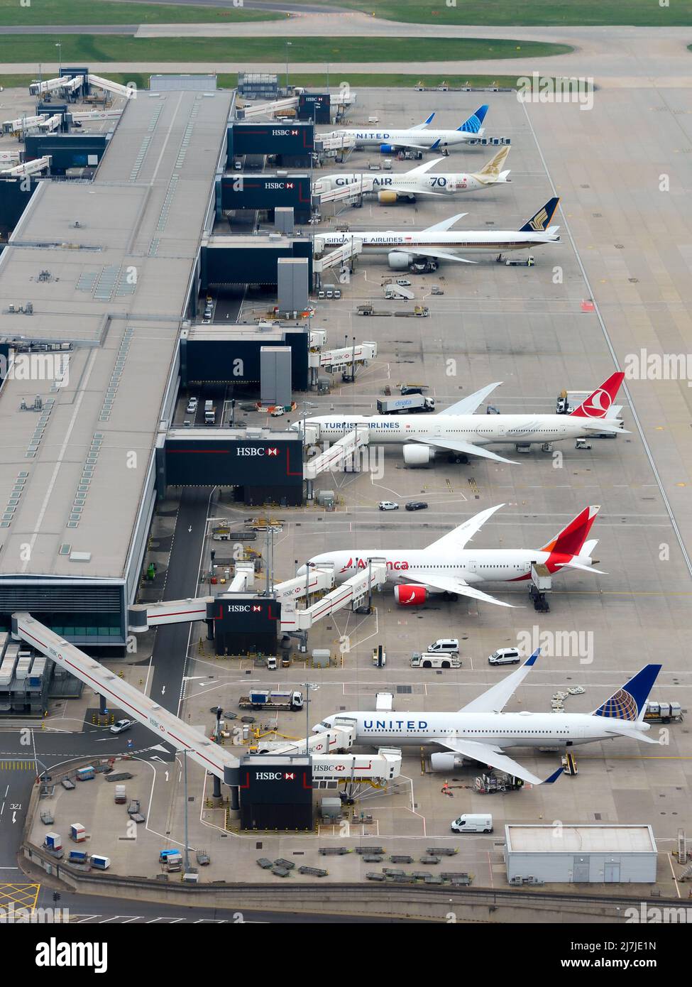 Heathrow Airport Terminal 2 Luftaufnahme, auch bekannt als Queen's Terminal. Vielbeschäftigter Flughafenterminal in Großbritannien mit mehreren Flugzeugen. Stockfoto