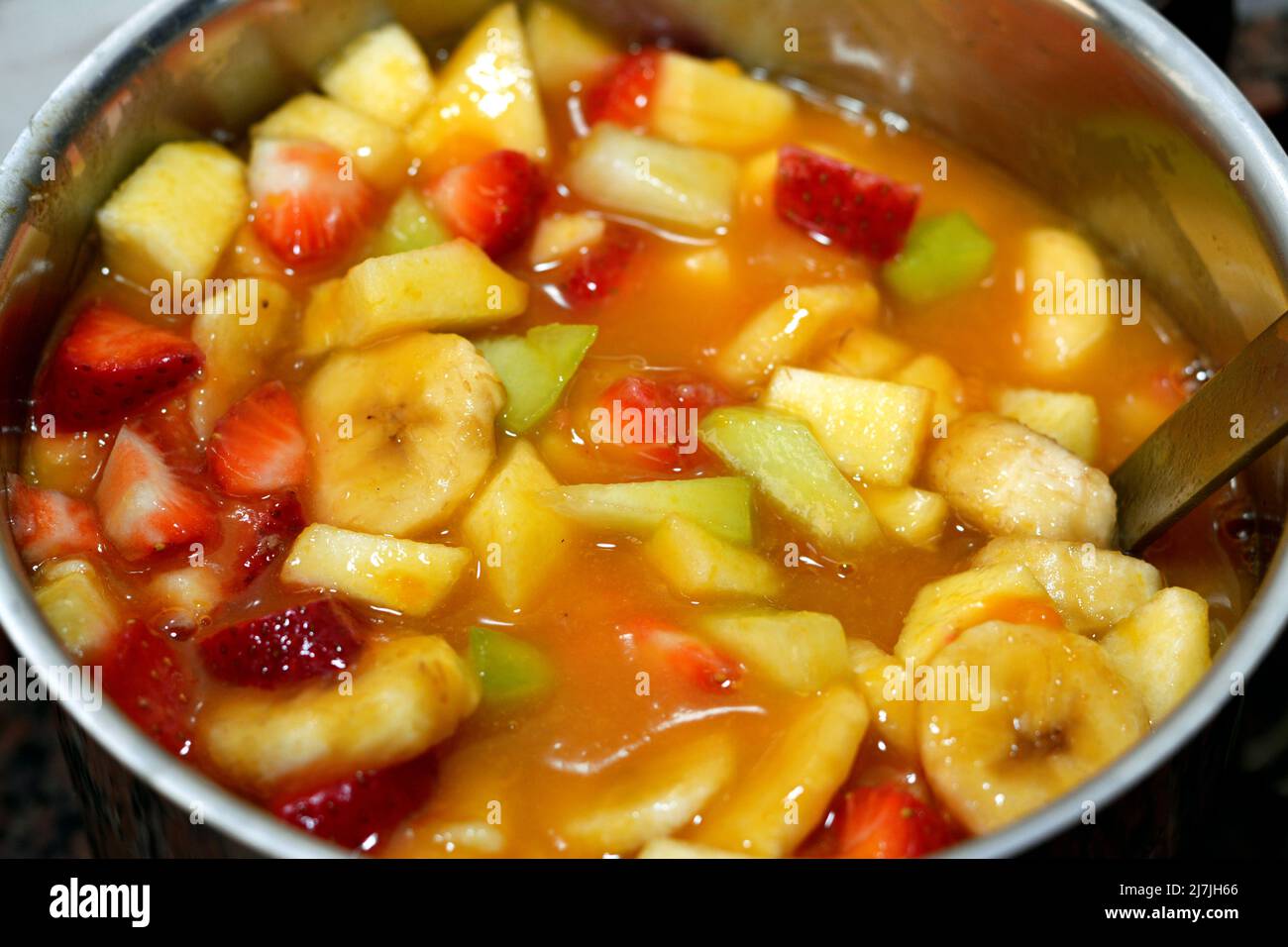 Eine Schüssel Obstsalat aus Scheiben von Bananen, Erdbeere, Cantaloupe, Äpfel und Saft von Mango und Orange gemischt, selektive Fokus eines Fre Stockfoto