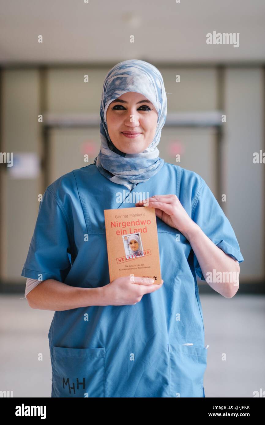 Hannover, Deutschland. 29. April 2022. Die Intensivpflegerin Farah Hareb-Demir hält das Buch „Nowhere a Country“ auf dem Campus der Medizinischen Hochschule Hannover (MHH) in der Hand. In dem Buch beschreibt die Krankenschwester ihre Geschichte zusammen mit dem Journalisten Gunnar Menkens. Hareb-Demir lebt seit mehr als 30 Jahren in Deutschland, doch trotz mehrerer Gerichtsverfahren und eines unbefristeten Arbeitsvertrages drohen die Einwanderungsbehörden ihr weiterhin mit Abschiebung. (To dpa 'unklare Identität: Intensivkrankenschwester immer noch nur toleriert') Quelle: Ole Spata/dpa/Alamy Live News Stockfoto