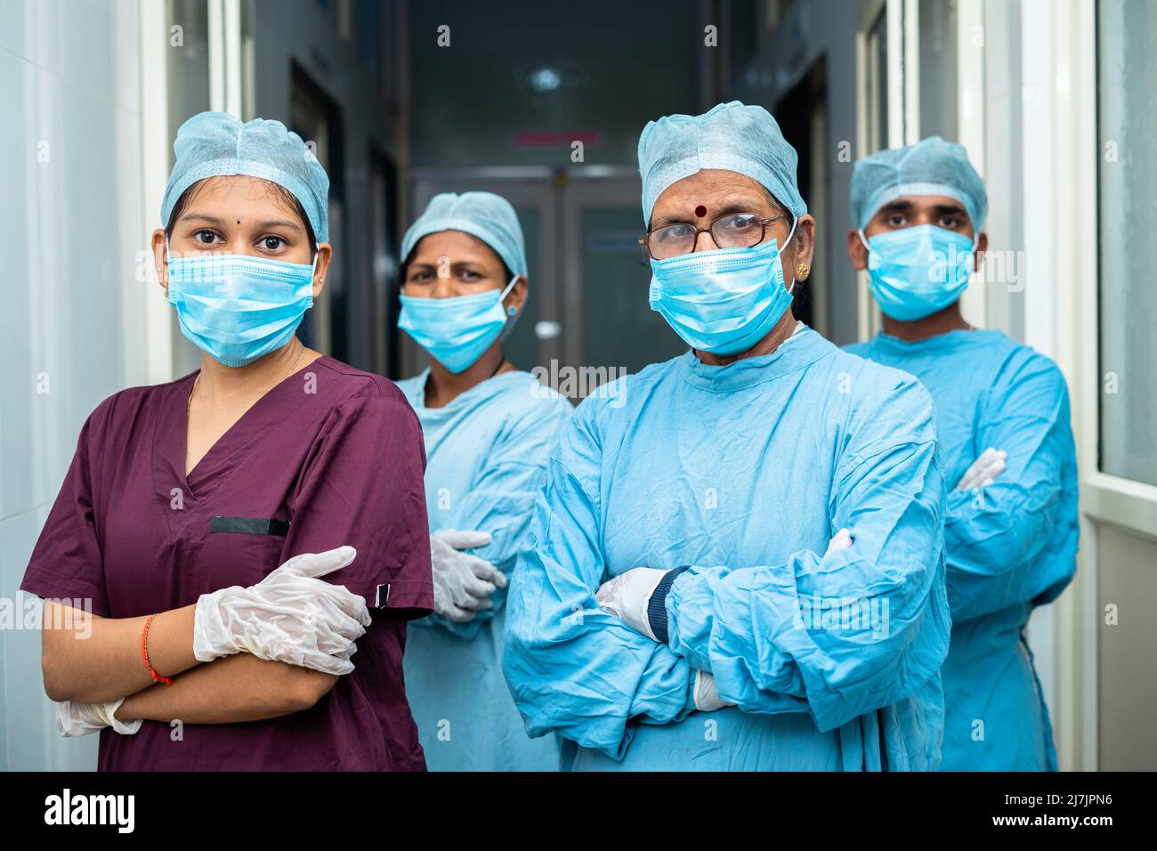 Gruppe von Chirurgen und Praktikern zuversichtlich stehen mit den Armen gekreuzt durch Blick Kamera auf Krankenhauskorridor - Konzept der Gesundheitsversorgung und Medizin Stockfoto