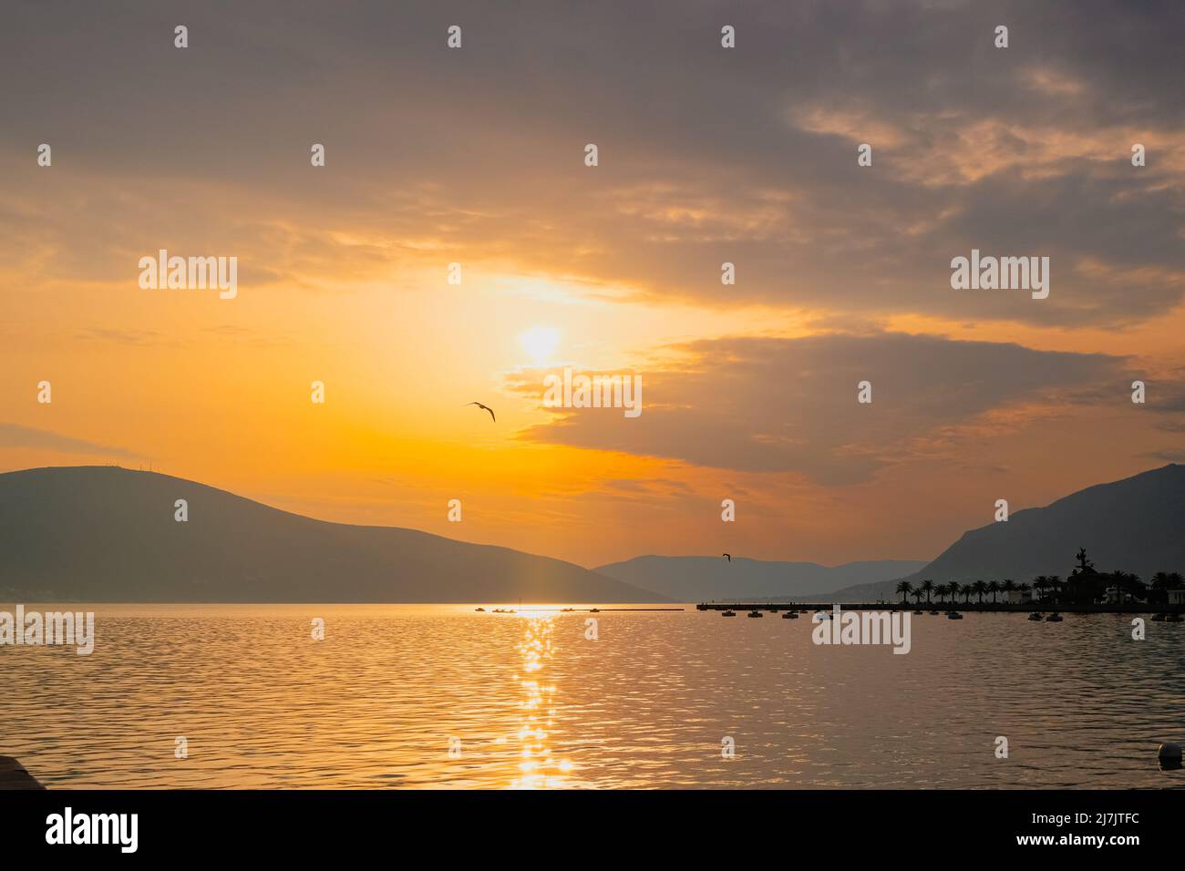 Schöne orange Sonnenuntergang mit Wolken, fliegenden Vogel, Berge und Reflexion im Meer. Entspannung und Meditation Paradies Orte der Welt. Schönheit Stockfoto
