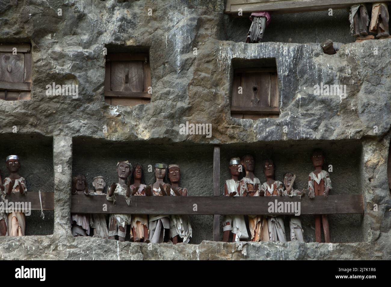 Steingrabeöffnungen und Holzraster auf einer Klippe an einer traditionellen Grabstätte in Lemo, Nord-Toraja, Süd-Sulawesi, Indonesien. Stockfoto