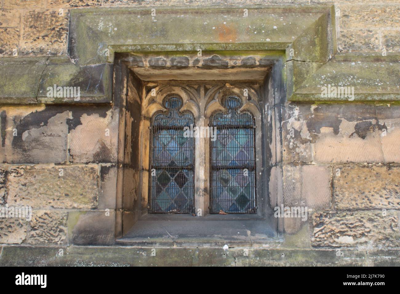 Steinfensterrahmen mit Diamant-Buntglasformen, die von Blei in einer mittelalterlichen Kirche gehalten werden Stockfoto