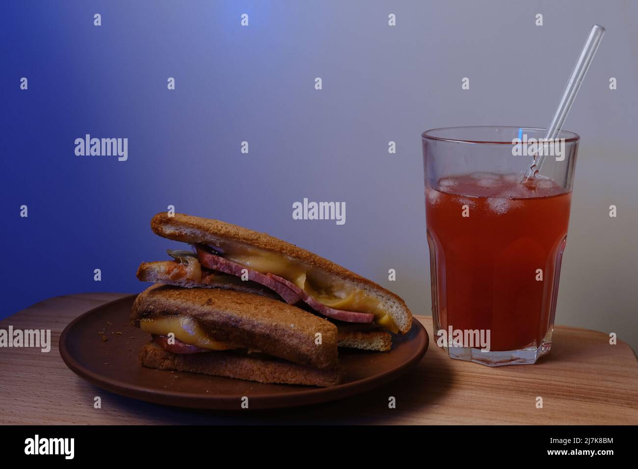 Sandwich mit Wurst und Käse mit Rotsoda mit Eis im Glas mit Stroh Stockfoto