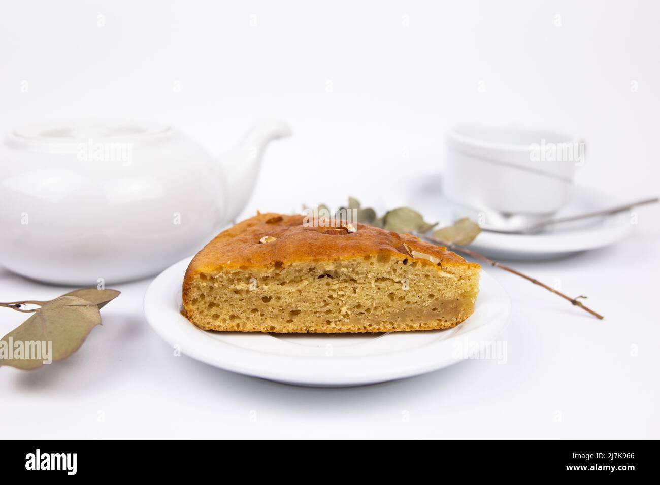 Stück Kuchen auf einer Untertasse mit einer Tasse Tee oder Kaffee und einem Wasserkocher Stockfoto
