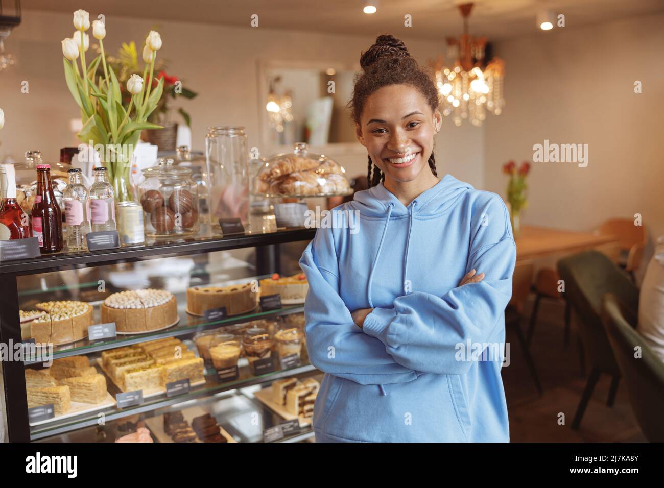 Schöne junge, fröhliche Kundin der Kaffee- und Konditorei lächelt vor der Kamera. Stockfoto