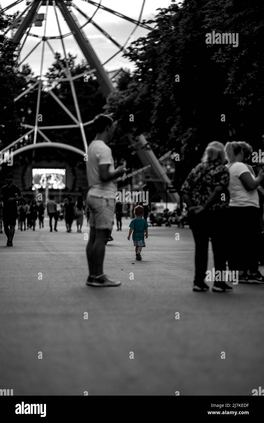 Ein kleiner Junge geht unter der Menschenmenge im Park. Schwarzweiß-Foto Stockfoto