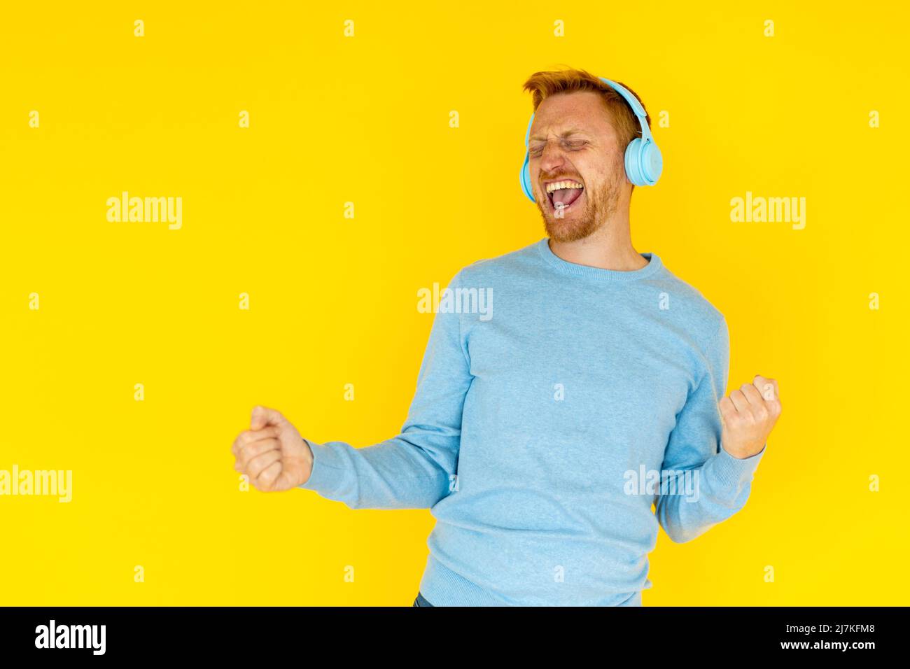 Glücklicher junger erwachsener hispanic Latino Mann, der vor gelbem Hintergrund tanzt Stockfoto