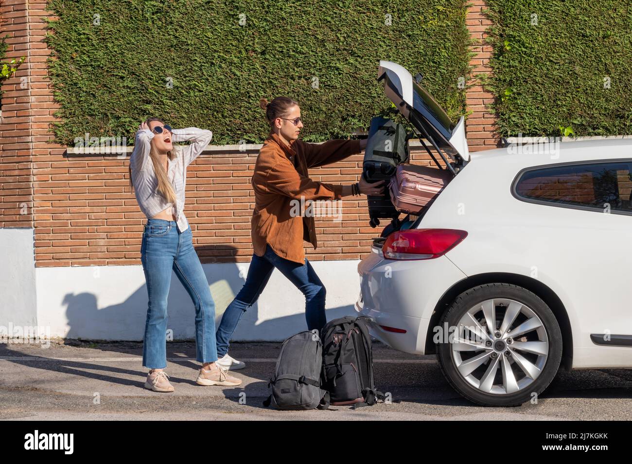 Junge Männer und Frauen verzweifelt, dass ihre Taschen nicht in den Amletero des weißen Autos steigen, um zum Flughafen zu fahren Stockfoto