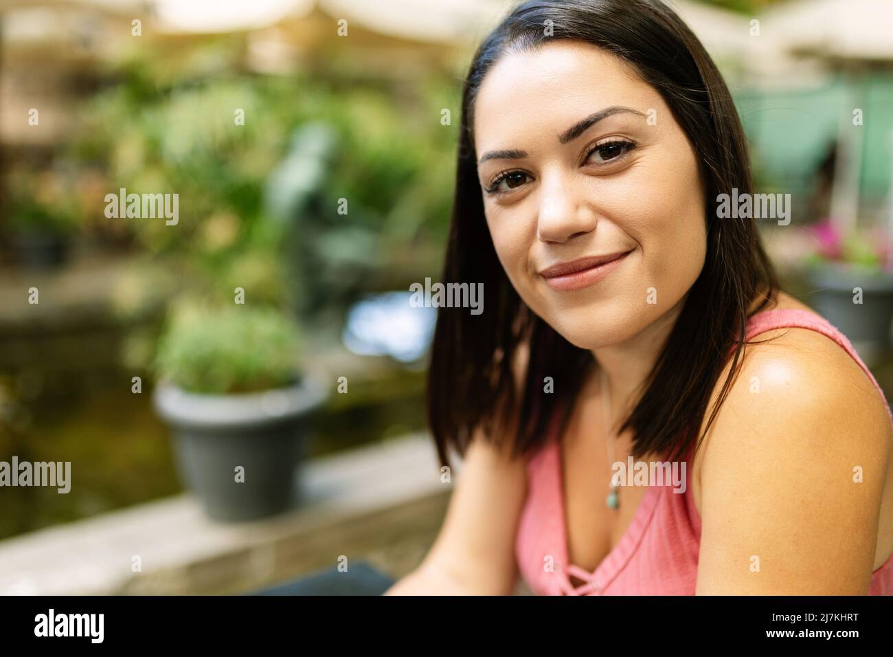 Porträt einer jungen kaukasischen Frau, die die Kamera im Freien betrachtet und sich entspannt Stockfoto