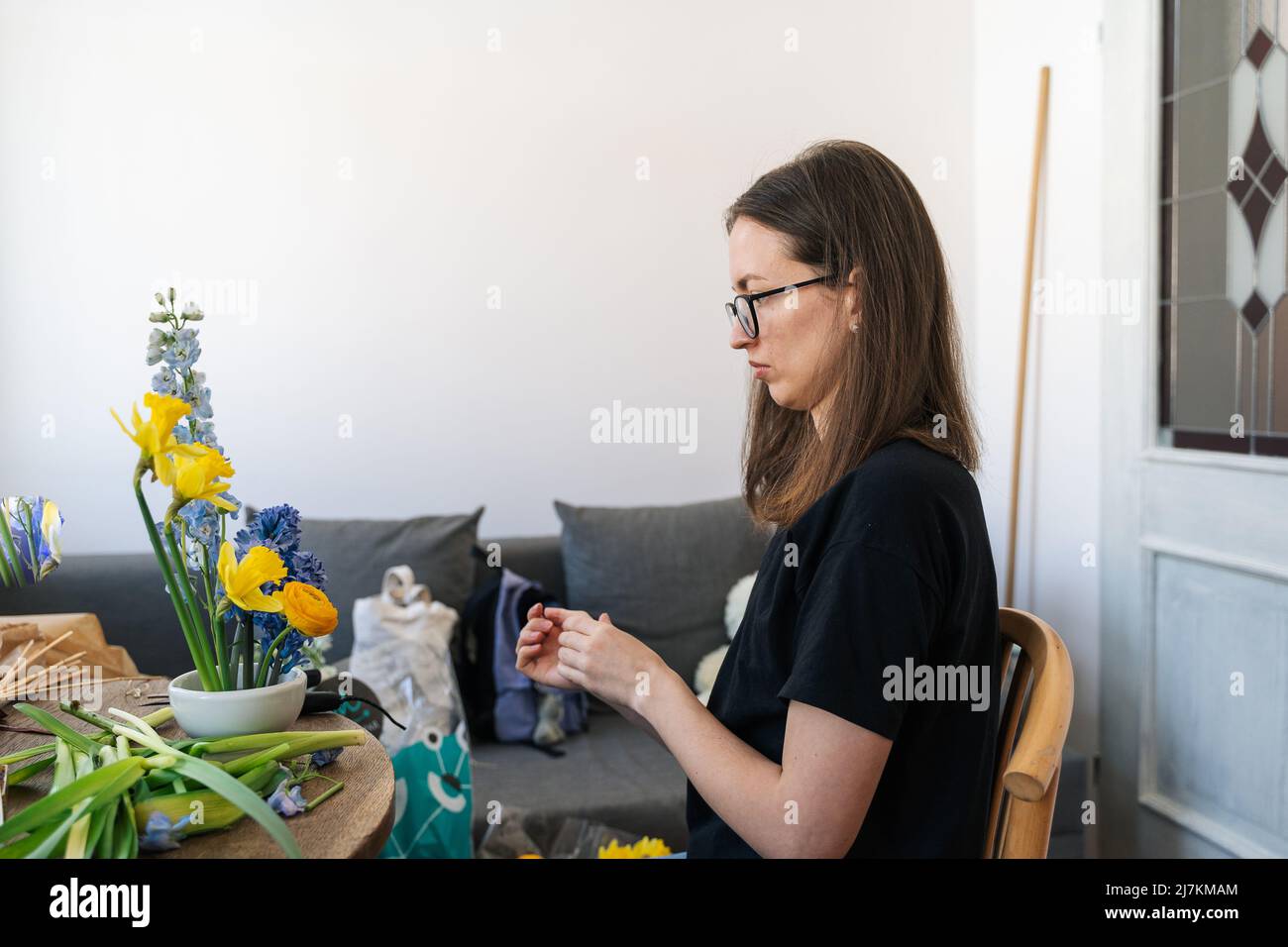 Seitenansicht des Fokus weibliche Florist am Tisch tun Ikebana japanische Kunst der Blumenarrangement-Stil zu Hause Stockfoto