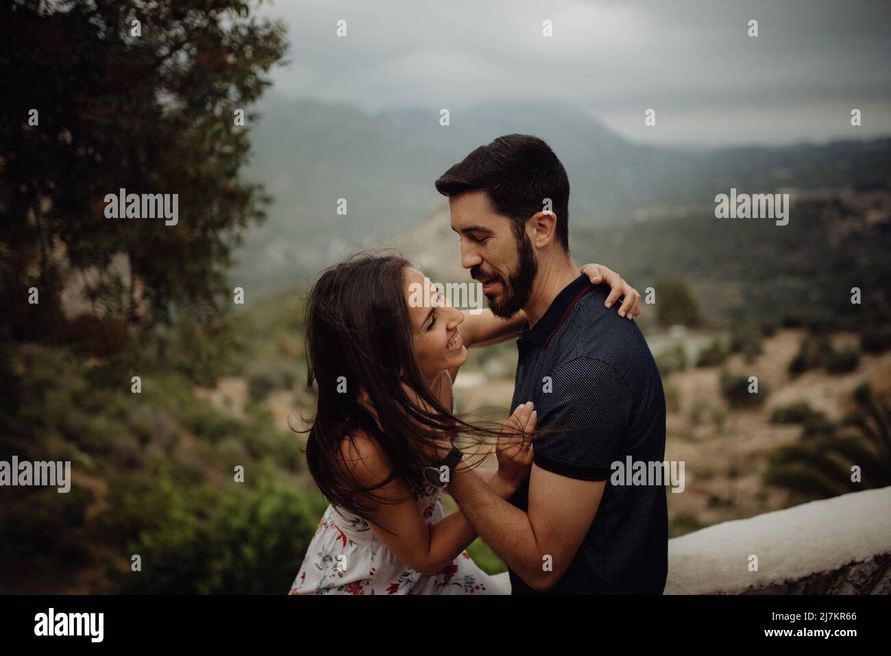 Seitenansicht eines glücklichen lächelnden Paares, das sich umarmte und ansah Einander beim Schleifen in nebliger Landschaft am Sommertag Stockfoto