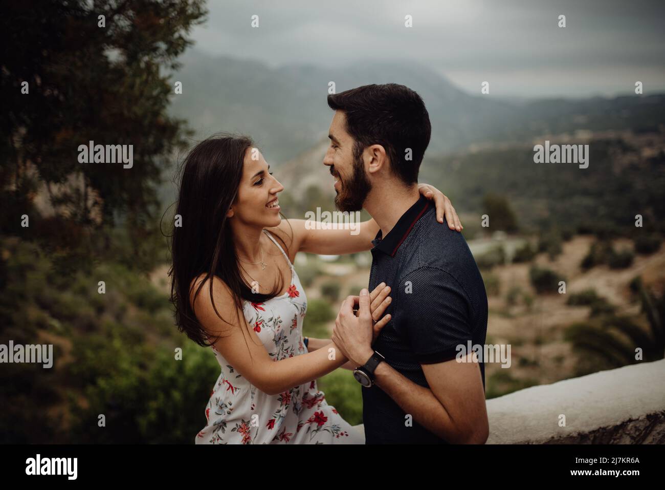Seitenansicht eines glücklichen lächelnden Paares, das sich umarmte und ansah Einander beim Schleifen in nebliger Landschaft am Sommertag Stockfoto