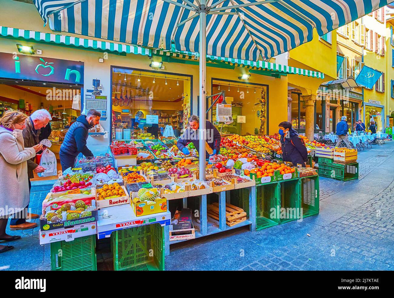 LUGANO, SCHWEIZ - 25. MÄRZ 2022: Der große Obststand mit frischen Orangen, Äpfeln, Kiwi, Granatäpfeln und anderen Früchten in der schmalen Via Pessina, ON Stockfoto