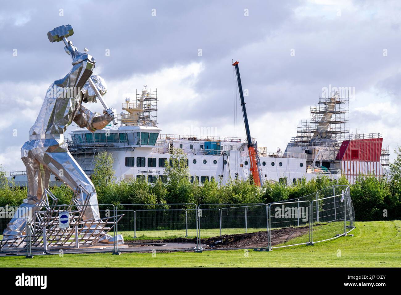 Die Skulptur „Shipbuilders of Port Glasgow“ neben der Ferguson Marine Werft in Port Glasgow, Inverclyde. Während der Bau von zwei Fähren im Auftrag von CalMac, Schottlands öffentlichem Fährunternehmen, wurde Ferguson Marine Engineering Ltd in die Verwaltung genommen, da die Kosten ansprangen und sich der Bau verzögerte. Die schottische Regierung verstaatlichte die Werft im Dezember 2019 in Ferguson Marine (Port Glasgow) Holdings, um Arbeitsplätze und den Vertrag zu retten. Bilddatum: Dienstag, 10. Mai 2022. Stockfoto