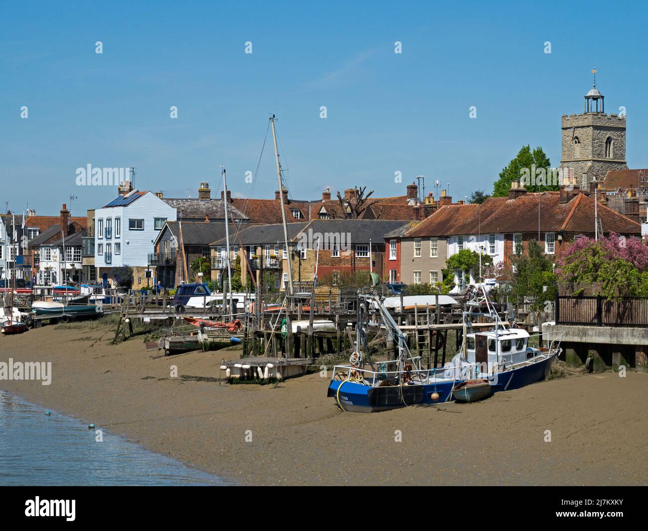 Boote, die am Strand vor der Mündung des Flusses Colne festgemacht wurden, mit den alten Gebäuden der Stadt Wivenhoe, Essex, England, Großbritannien Stockfoto