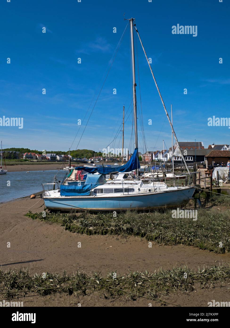 Am Strand vor der Mündung des Flusses Colne festmachen Segelboote zusammen mit dem Gebäude der antiken Stadt Wivenhoe, Essex, England, Großbritannien Stockfoto