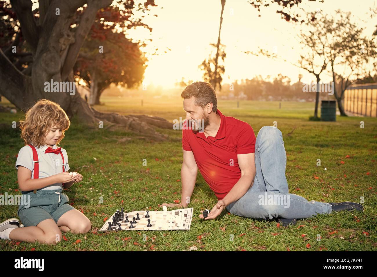 Vater und Sohn spielen Schach auf Gras im Sommerpark, Vaterschaft Stockfoto