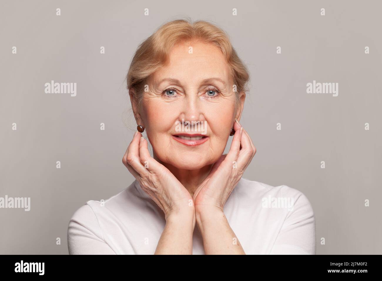 Lächelnde ältere Frau mittleren Alters, die die Kamera anschaut, glückliche alte Dame, die drinnen posiert. Positive Single Senior Female Headshot Portrait Stockfoto