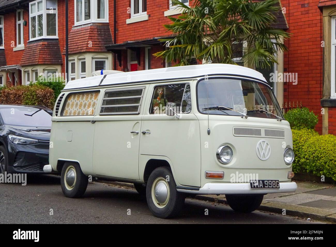 Ein Oldtimer-Wohnmobil von Volkswagen, der in einer Vorstadtstraße geparkt ist und den Lebensstil des Wohnwagens illustriert. Stockfoto