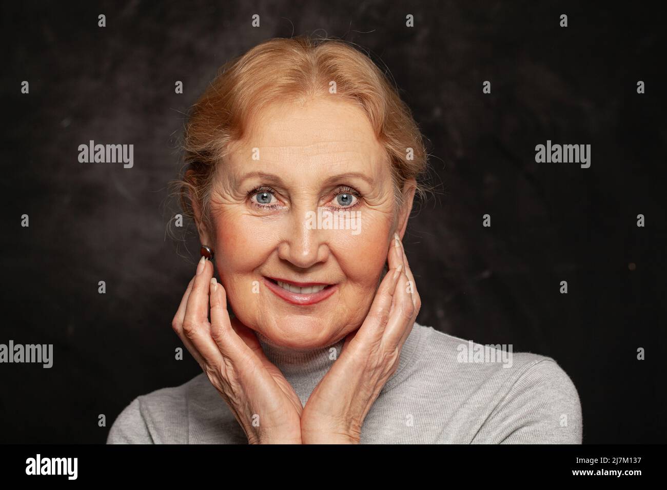 Schöne Frau mittleren Alters mit einem niedlichen Lächeln auf schwarzem Hintergrund Porträt Stockfoto