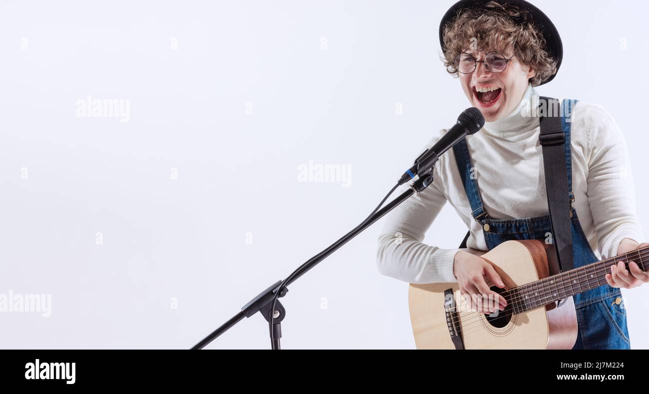 Porträt eines jungen Emotiona-Mannes, Musiker, der akustische Gitarre spielt und singt. Konzept von Kunst, Musik, Stil und Kreation Stockfoto