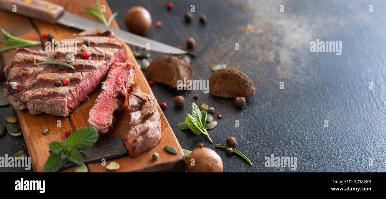 Gegrillte Rinderfilet-Steaks auf dunklem Tisch aus nächster Nähe. Portioniertes Filet Mignon mit Gewürzen und Kräutern. Konzept der Sommerkost, Fleischesser. Stockfoto