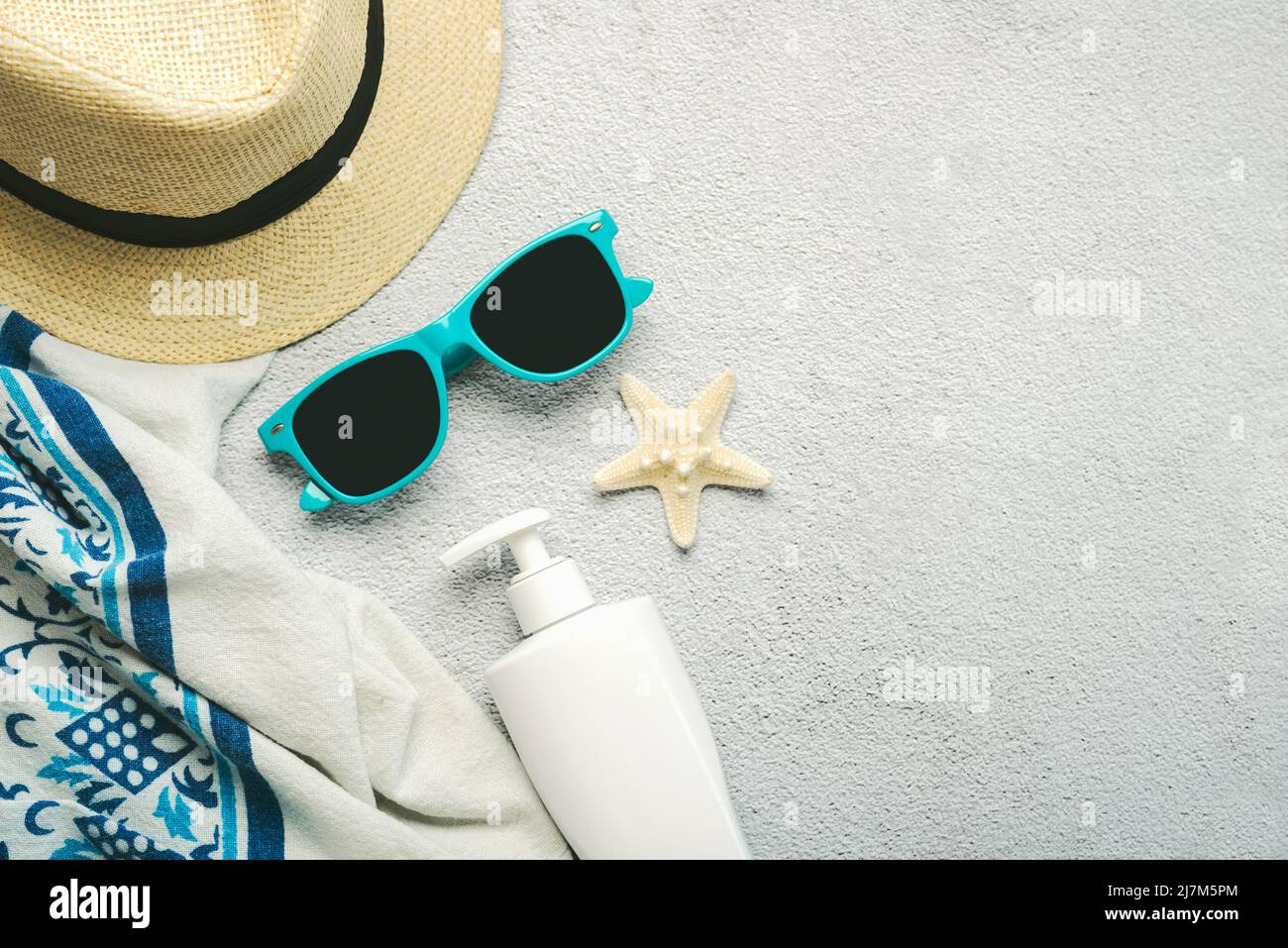 Sommerferienkonzept. Draufsicht auf Strandtuch, Sonnenbrille, Hut und Sonnencreme mit Platz für Text über grunge Hintergrund Stockfoto