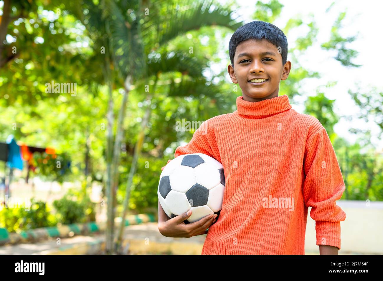 Fröhliches Teenager-Kind hält Fußball, indem Sie mit der Kamera auf den Garten mit Kopierraum - Konzept der Kindheit Lebensstil, zukünftige Ziele und Wochenendferien Stockfoto