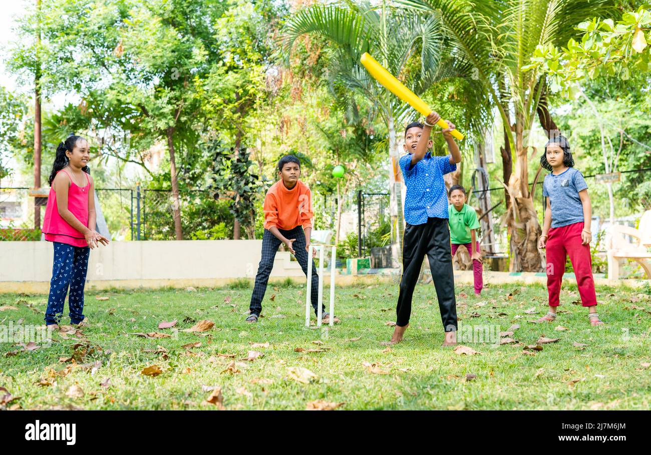 Kleines Kind, das beim Spielen von Cricket im Park auf den Ball trifft, um Punkte zu erzielen - im Gleichklang mit körperlichen Aktivitäten, Vitalität und Unterhaltung in der Kindheit Stockfoto
