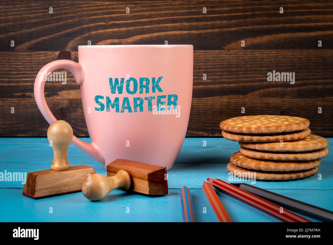 Intelligenter Arbeiten. Kaffeetasse mit Text auf einem blauen Schreibtisch. Stockfoto