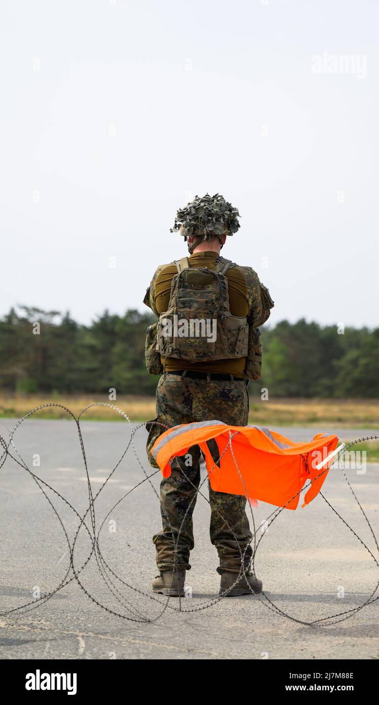 Münster, Deutschland. 10.. Mai 2022. Ein Bundeswehrsoldat sperrt während der Übung Wettiner Heide eine Straße ab. Die Übung findet mit bis zu 7.500 Soldaten aus neun Nationen im Zentrum der Trainingsgebiete Bergen und Münster in Niedersachsen statt. Quelle: Philipp Schulze/dpa/Alamy Live News Stockfoto