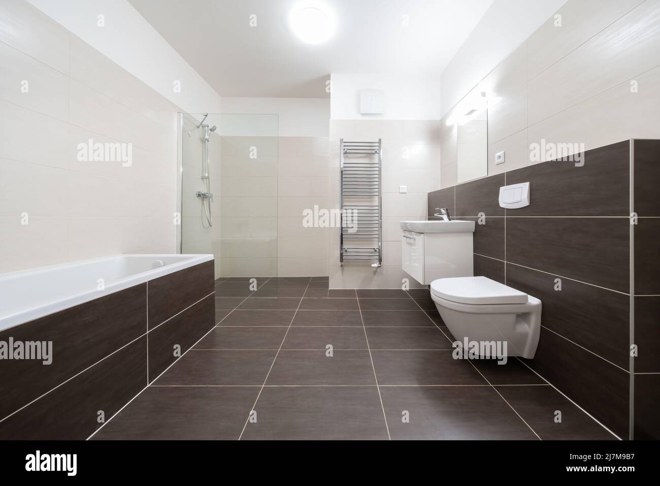 Celadna, Tschechien - 05.07.2022: Leeres Bad im modernen, zeitgenössischen Stil mit braunen Fliesen und weißen Wänden und Decken. Badewanne, hängende Toilette und Stockfoto
