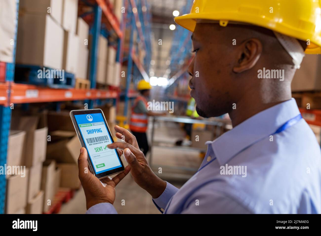 Nahaufnahme eines jungen afroamerikanischen Arbeiters, der die Lieferung über ein digitales Tablet im Lager verfolgt Stockfoto