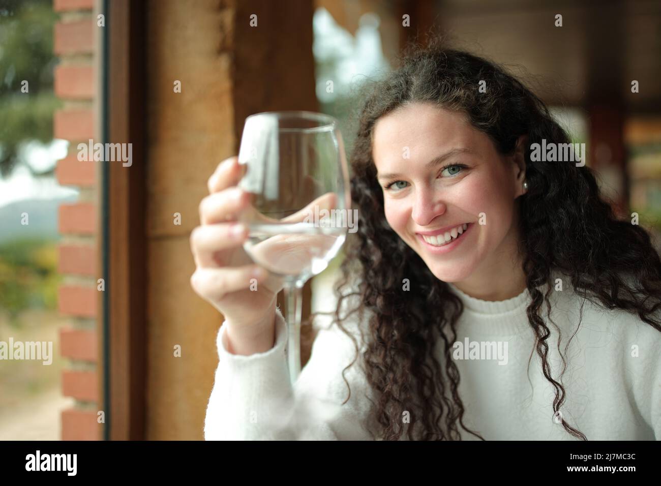 Eine glückliche Frau, die ein Glas Wasser in einem Restaurant hält Stockfoto