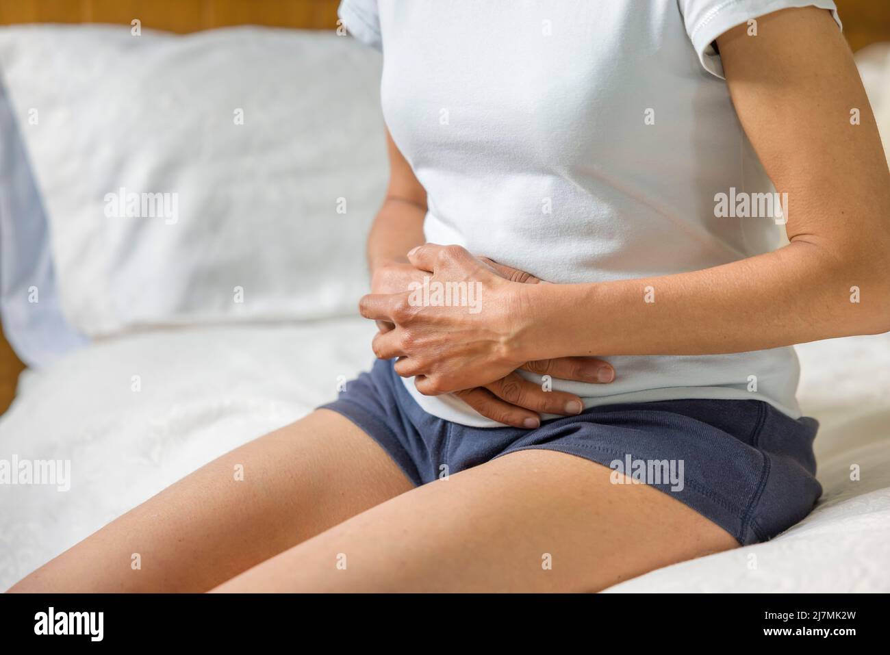 Frau, die den Magen mit Krämpfen oder Schmerzen hält. Weiblich mittlerer Erwachsener Asian Indian, UK Stockfoto