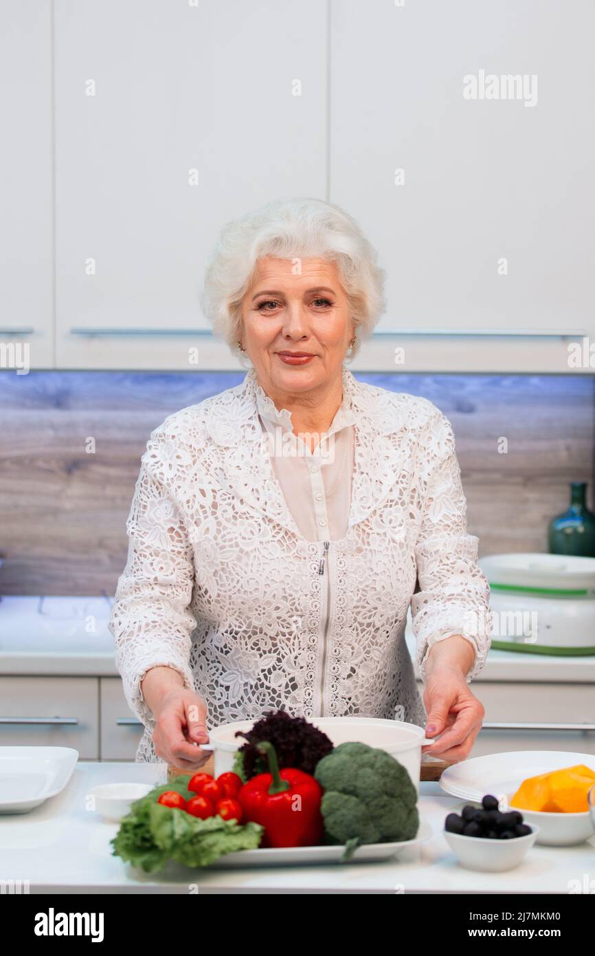 Eine ältere Frau mit guter Laune kocht gesunde Lebensmittel in der Küche Stockfoto