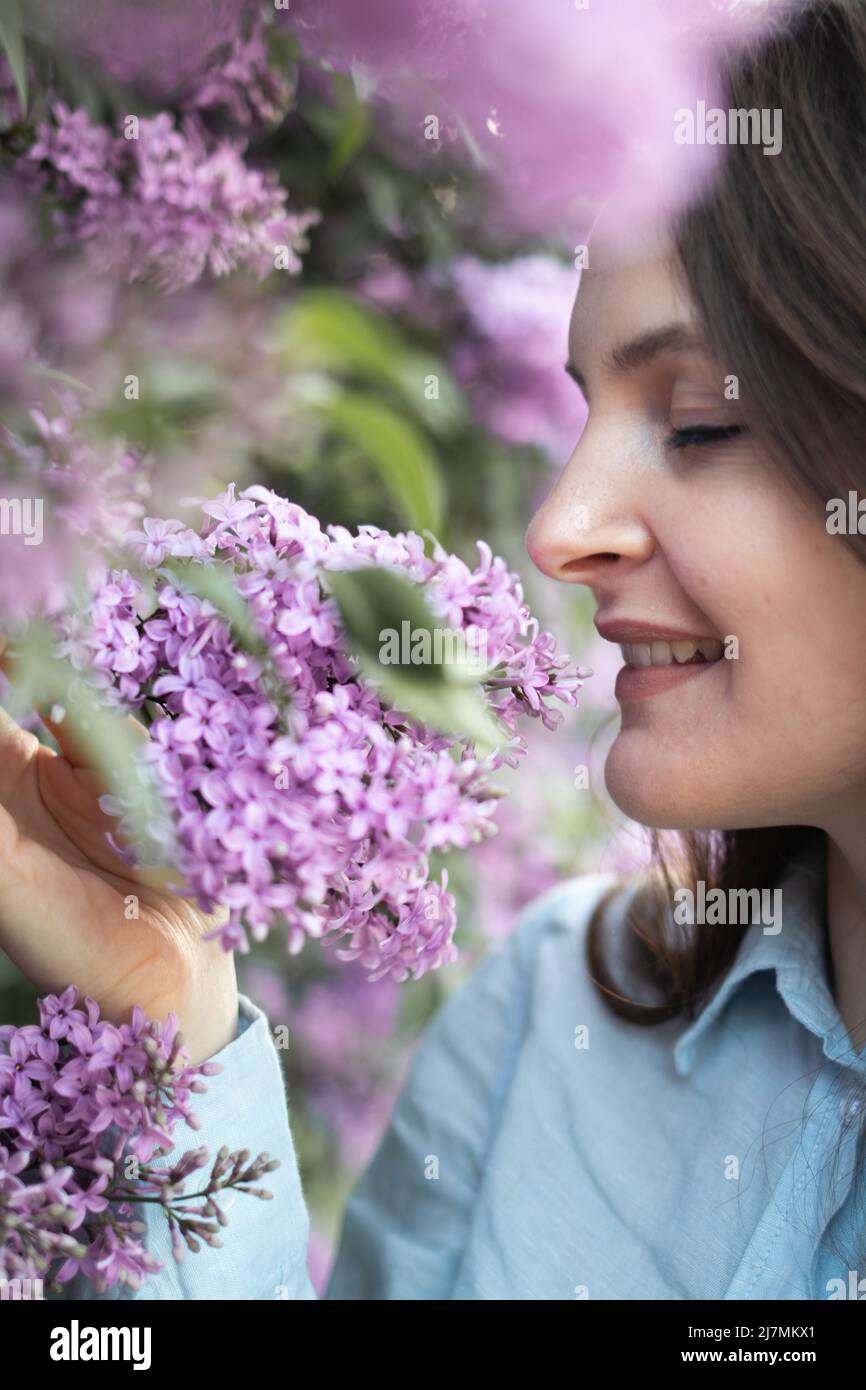 Junge schöne Brünette Frau riecht Fliederblüte im Frühling Stockfoto