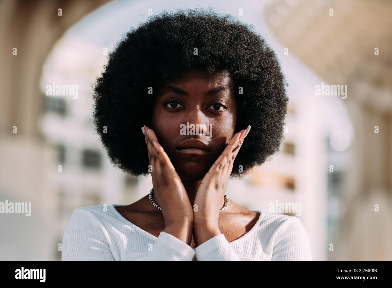 Porträt einer jungen schwarzen Aktivistin mit afrohaarigen Gesten mit ihren Händen in V-Form. Horizontal Stockfoto