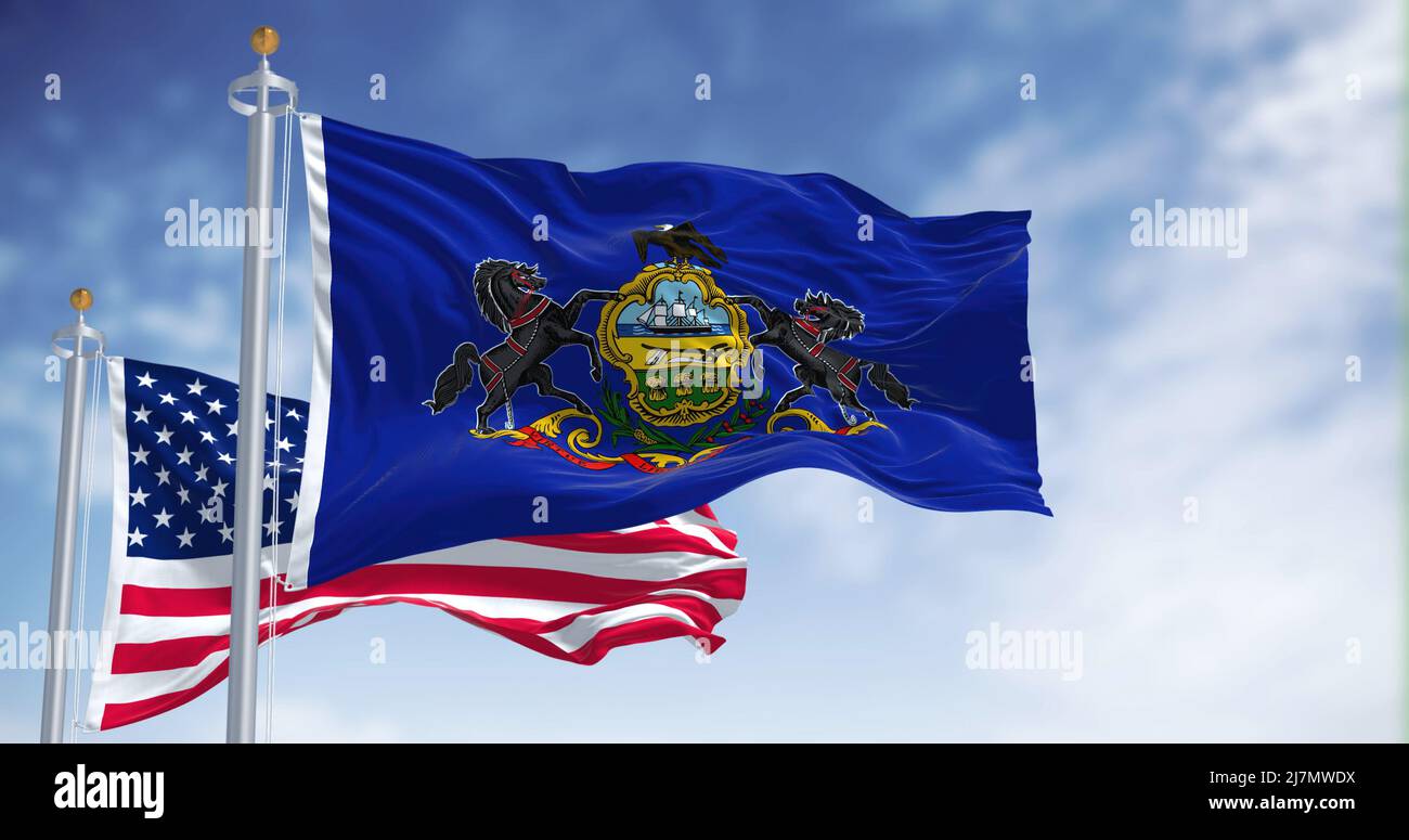 Die Staatsflagge von Pennsylvania winkt zusammen mit der Nationalflagge der Vereinigten Staaten von Amerika. Im Hintergrund ist der Himmel klar. Pennsylvania Stockfoto