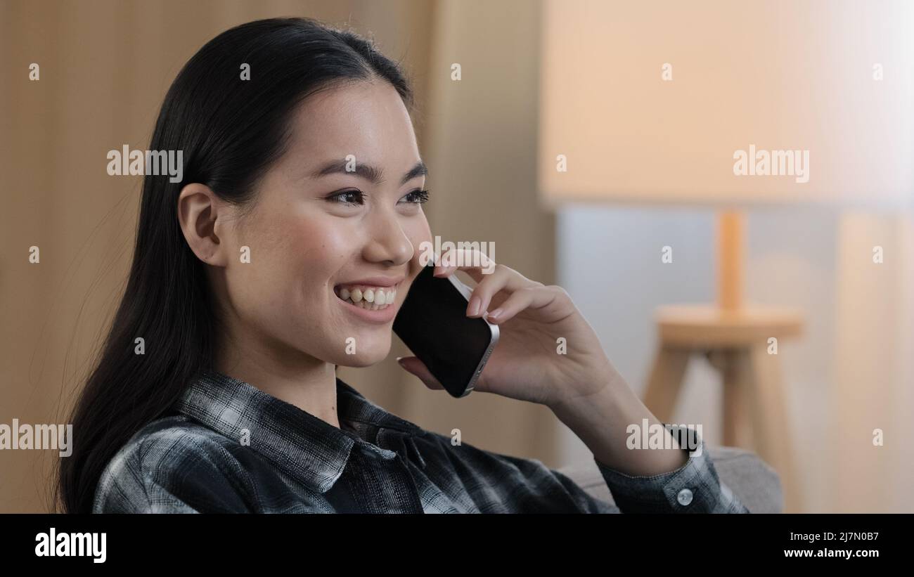 Lächelnd glücklich asiatische Frau Portrait Mädchen lächeln sprechen Handy zu Hause. Nahaufnahme koreanische Dame sprechen Smartphone flirten auf Telefon Stockfoto