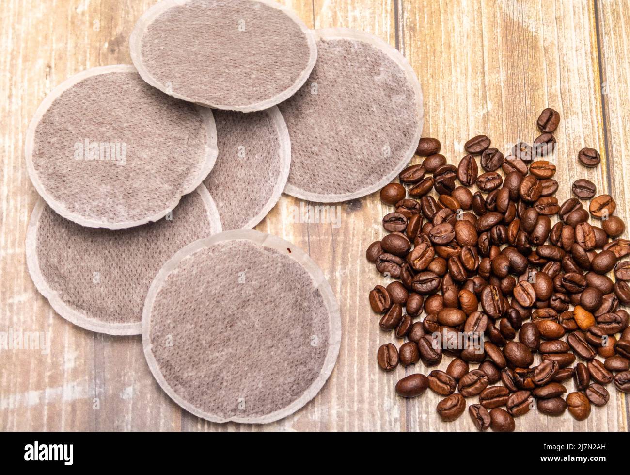 Draufsicht auf Kaffeepads und Kaffeebohnen auf einer rustikalen Holzoberfläche als Beispiel für verschiedene Kaffeerohprodukte. Flache Lay-Komposition Stockfoto