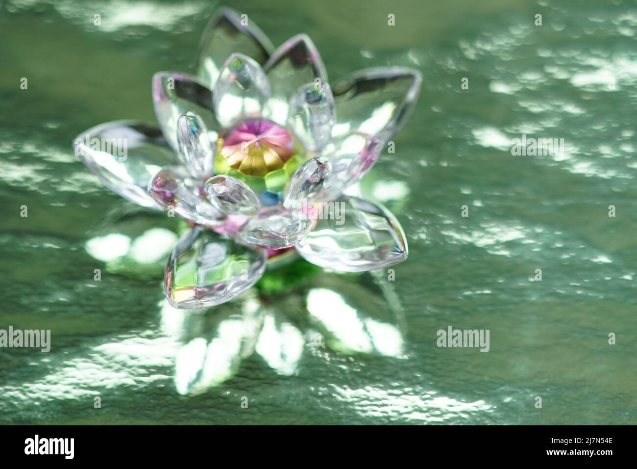 Kristalllotus auf glänzend grünem Hintergrund mit Lichtreflexion. Anahata Chakra-Symbol. Esoterische, reiki-Energie, Meditation, spirituelle Heilung. Stockfoto