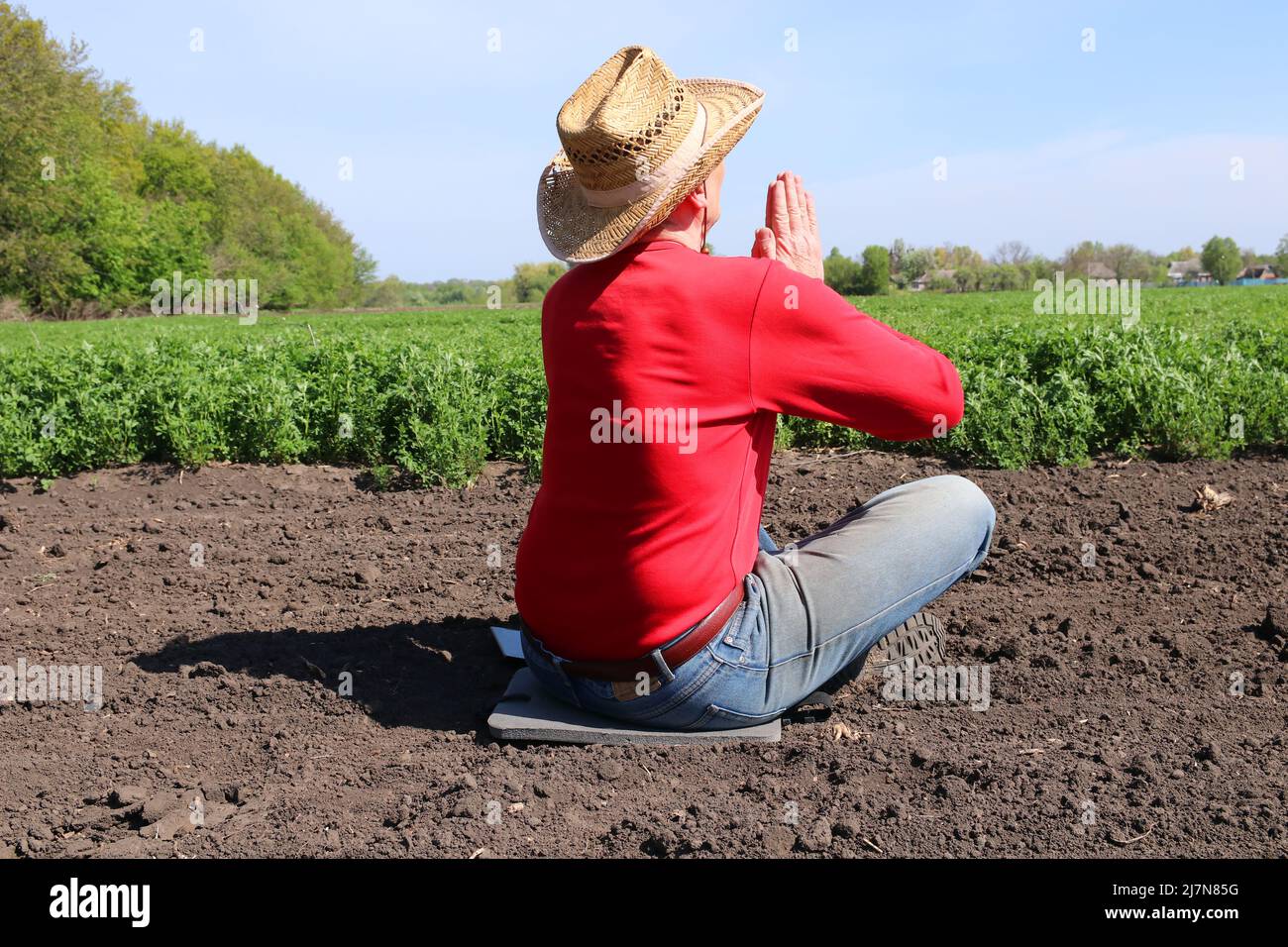 Ein ukrainischer Bauer betet in der Nähe seines Feldes. Ukrainische Landwirtschaft. Krieg in der Ukraine. Stockfoto
