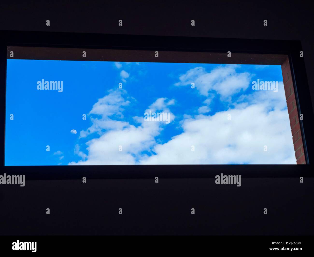 Blauer Himmel mit Wolken durch ein Fenster Stockfoto