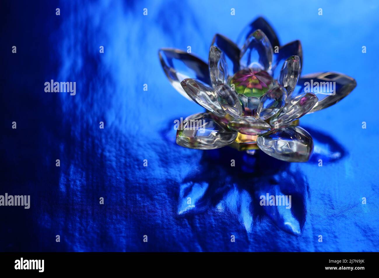 Kristalllotus auf einem dunkelblau glänzenden Tisch mit Lichtreflexion. Ajna-Chakra oder Symbol für das dritte Auge. Esoterische, reiki-Energie, Meditation, spirituelle Heilung Stockfoto