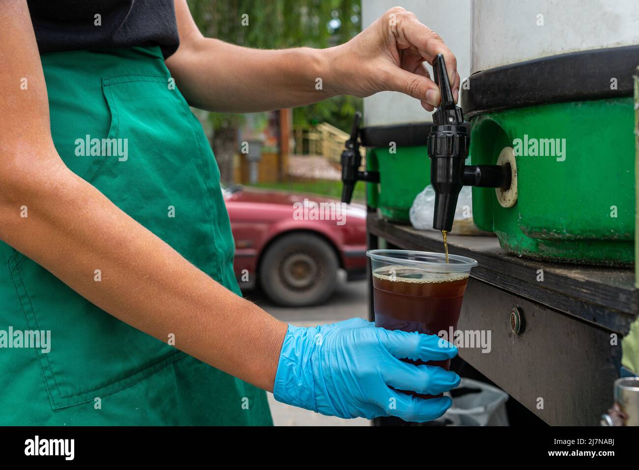 Frau gießt Bier aus Fass in ein Einwegglas. Stockfoto