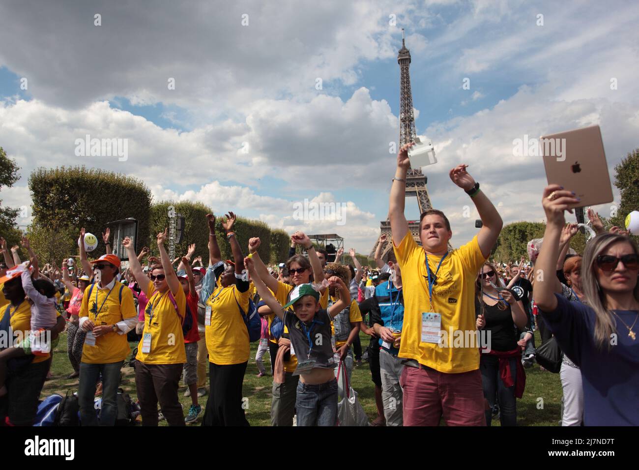 Bénévoles en t-Shirt jaune au concert de la Journée des oubliés des Vacances du Secours Populaire Français au Champs de Mars Tour Eiffel été 2015 Stockfoto