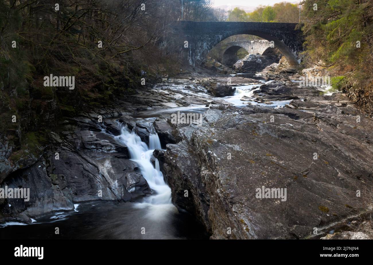 Der Wasserfall und zwei Brücken, die den Fluss im Dorf Invermoriston in Schottland, Großbritannien, überqueren Stockfoto