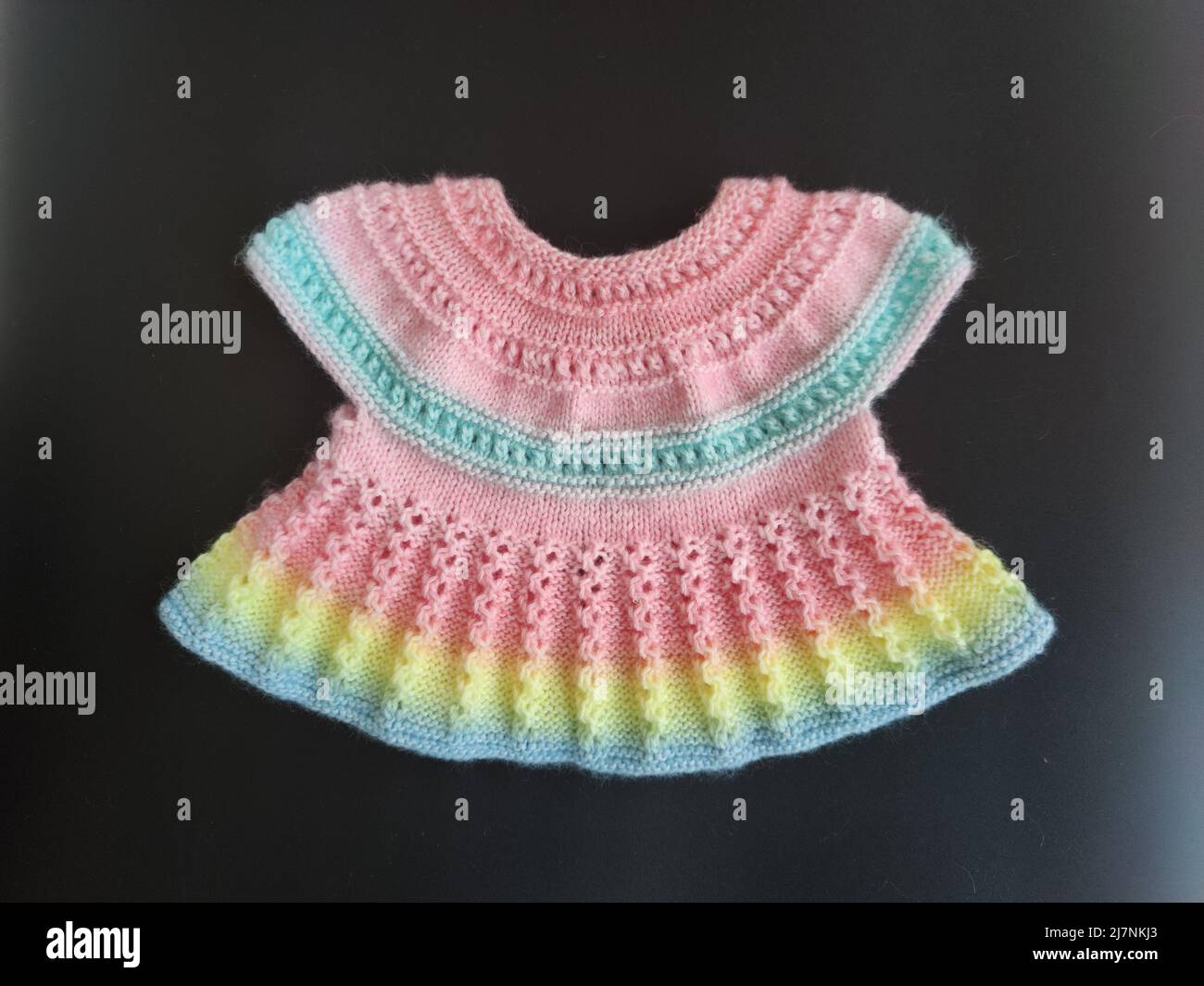 Bunte Strickkleid für Kinder Hintergrund. Babykleidung. Niedliches Regenbogen-Trikot für Kinder. Mode für Kinder. Ideen für handgefertigte Stockfoto